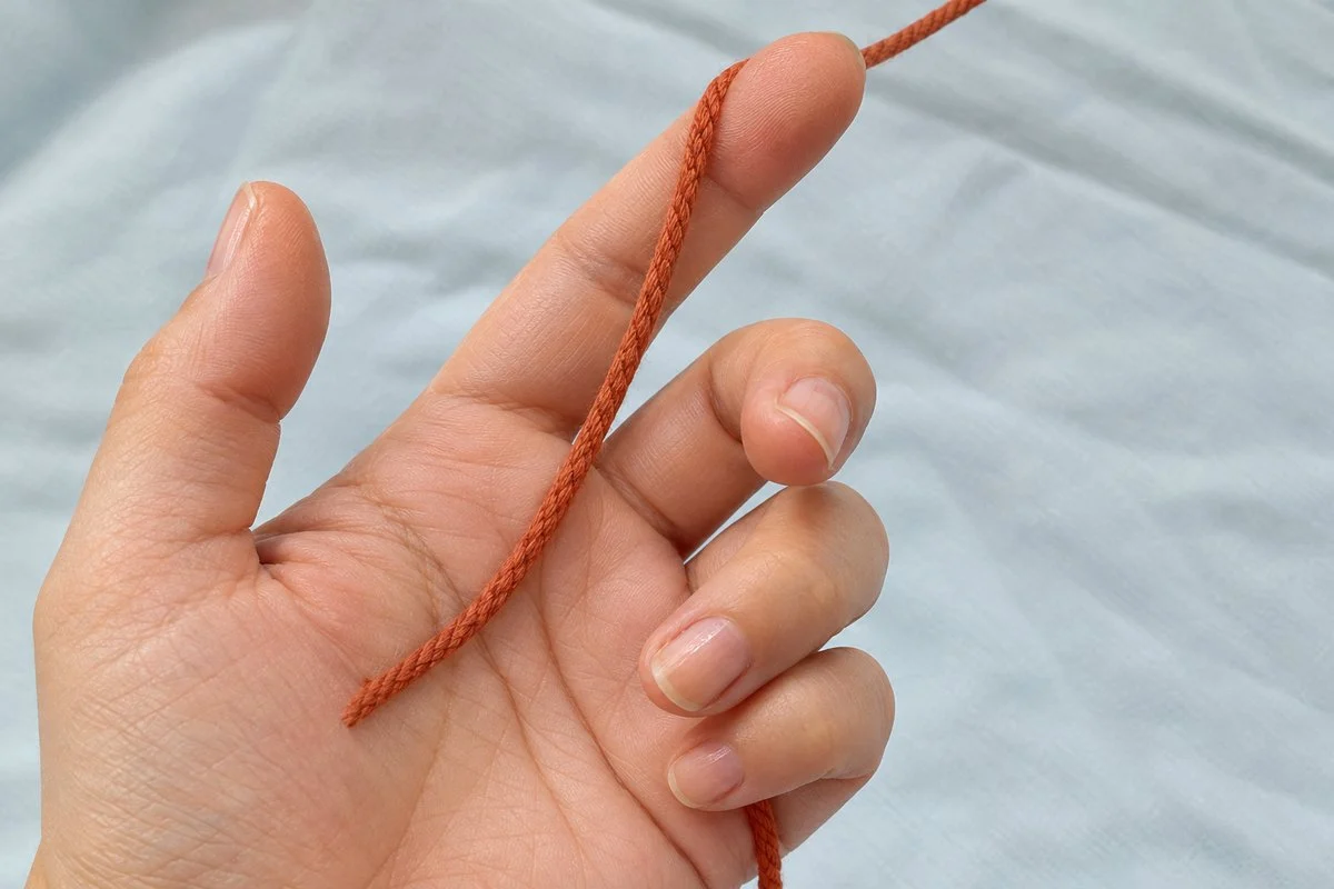 Left palm facing up with the terracotta yarn tail held under the ring finger and the working yarn over the index finger